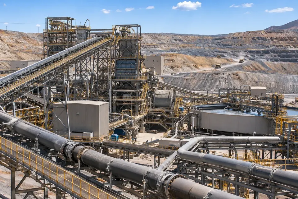 Mineral processing facility with ore conveyors and slurry pipelines at an open-pit mine